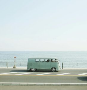 A classic Volkswagen van driving on a seaside road in Fujisawa, Japan, capturing a nostalgic coastal vibe.