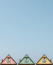 Three colorful triangular rooftops against a clear blue sky, showcasing simple architectural design.