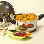 Colorful vegetable biryani cooked in a stainless steel pressure cooker with fresh ingredients.